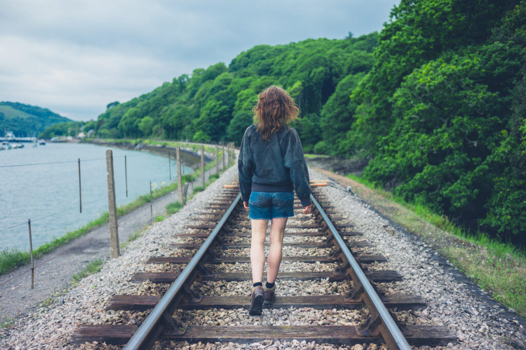 A young woman is walking on the railroad tracks