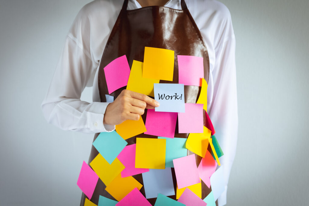 closeup woman wears apron with blank colorful sticky note paper holding a piece with "work" word, concept and idea showing busy