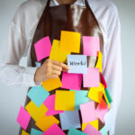 closeup woman wears apron with blank colorful sticky note paper holding a piece with "work" word, concept and idea showing busy