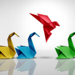 Innovative thinker concept and new idea thinking as a symbol of revolutionary innovation and inspiration metaphor as a group of paper swans and a game changer origami bird in flight.